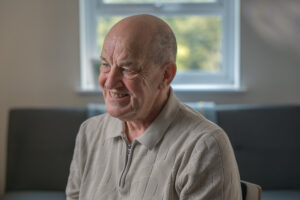 A man, Mick Davis, is sat being interviewed about his role as a foster carer.