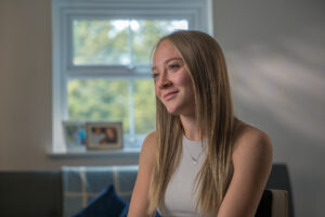 A young woman, Bebe Jackson, is sat to the right of frame. She's being interviewed about her experience as a child in foster care and her journey to becoming a para-athlete.